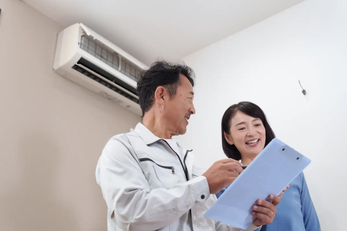 エアコンの前で相談している作業員と女性の顧客