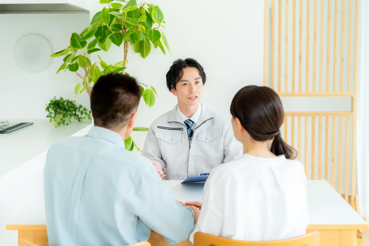 テーブルを挟んで対談する作業員と男女の顧客